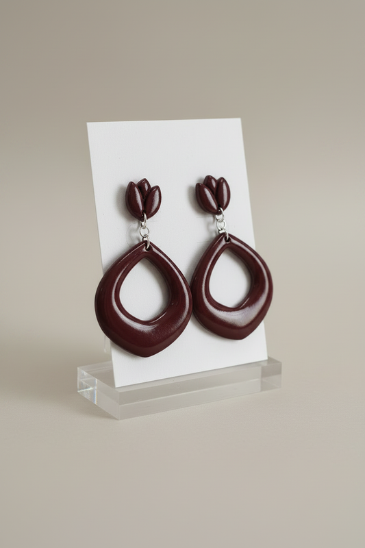 Handmade polymer clay Tulip Loop Earrings in Mauve Wine — deep dark burgundy tulip stud top with open teardrop hoop drop, displayed on a plain white jewellery card on a clear acrylic stand