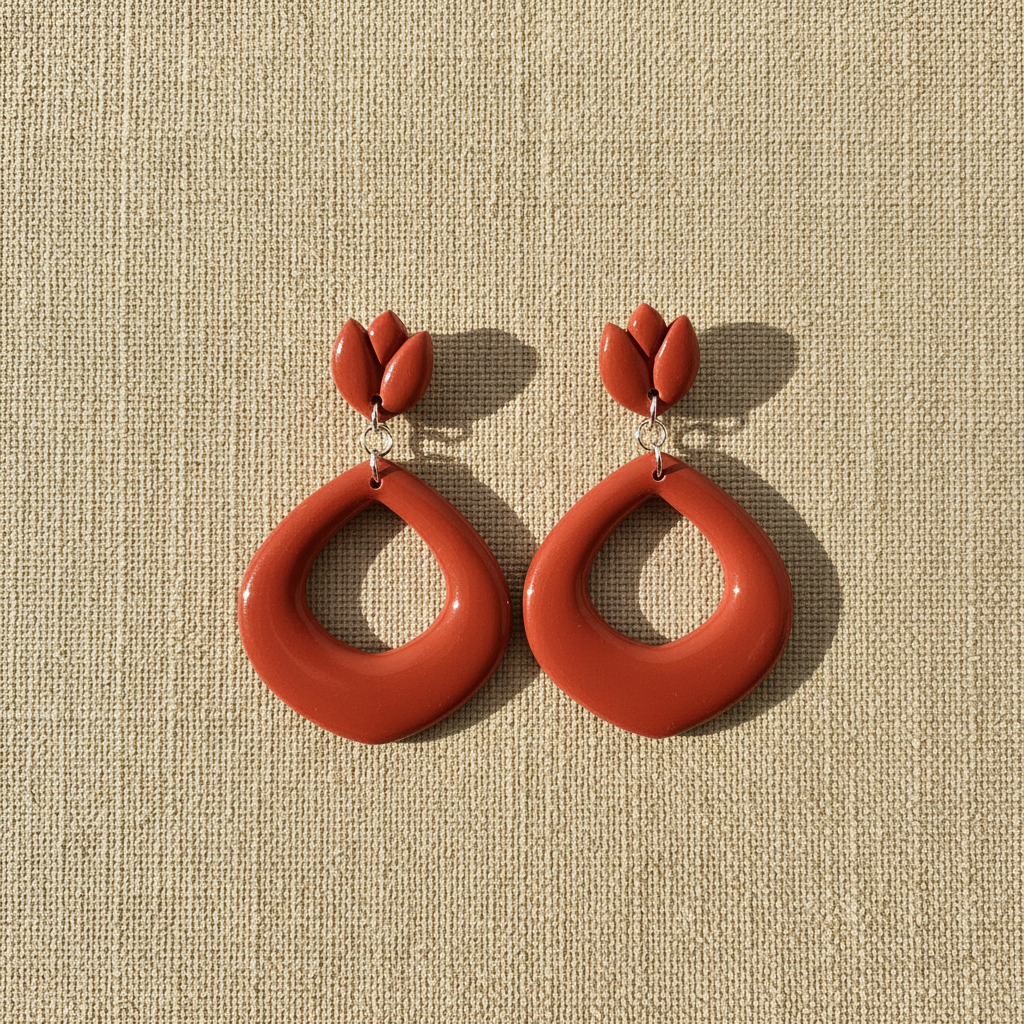 Flat lay of Crafty Larder Tulip Loop Earrings in Winterberry on a natural linen surface — handmade polymer clay dangle earrings in warm terracotta red