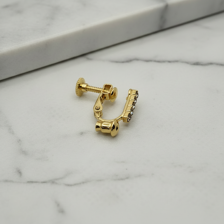18k gold plated clip-on converter for stud earrings with crystal rhinestone bar, shown on its side on soft grey marble surface — Crafty Larder