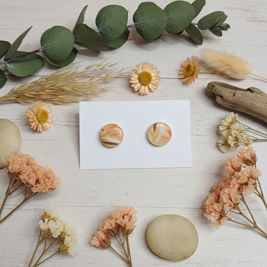 "Handmade polymer clay agate stud earrings with cream, peach, and coral marbled swirl pattern"