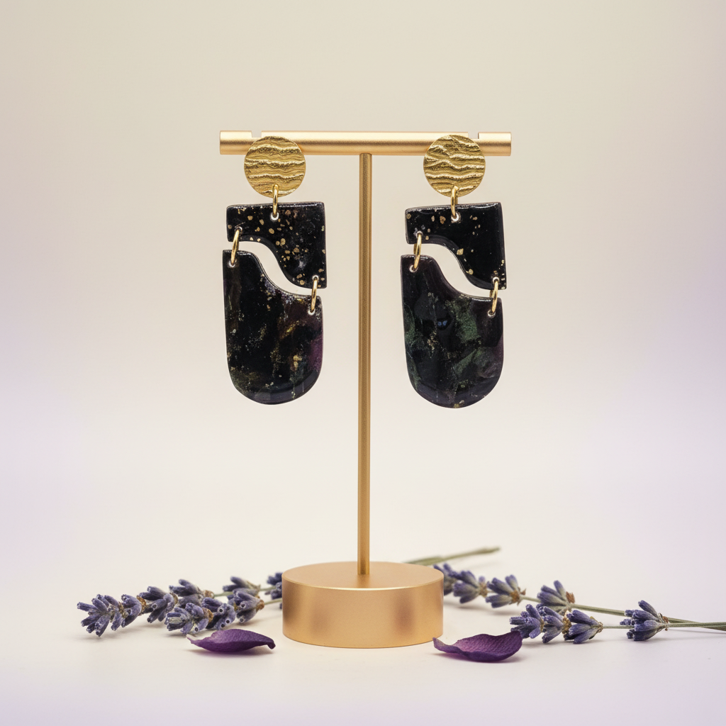 "Handmade polymer clay drop earrings with gold textured circular stud posts, black rectangular wavy cutout pieces and dark purple/black/gold mica shimmer elongated oval dangles"