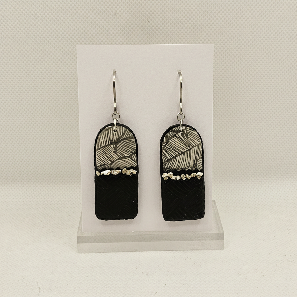 Handmade black polymer clay arch drop earrings with botanical leaf print and silver nuggets on plain white card, by Crafty Larder NZ