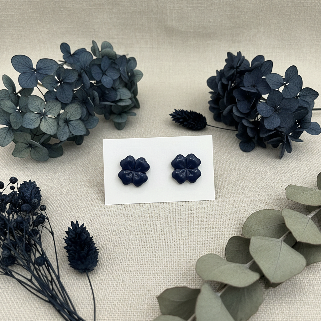 Briar Studs in Crown Blue — handmade polymer clay 5-petal flower stud earrings with clean etched petal lines and glossy finish, displayed on white card with deep blue dried hydrangeas and silver eucalyptus styling, handcrafted in New Zealand by Crafty Larder