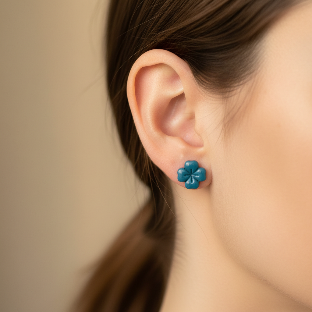 Woman wearing a Briar Stud in Lyons Blue, vibrant teal blue polymer clay flower stud with minimal etched petal lines, handcrafted in New Zealand by Crafty Larder