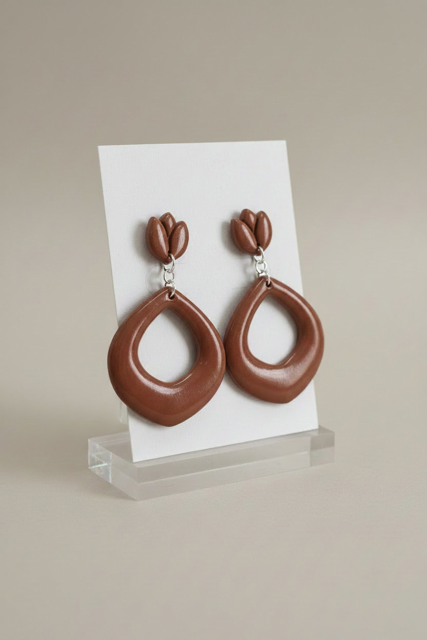 Handmade polymer clay Tulip Loop Earrings in Bronze Brown — warm earthy olive-brown tulip stud top with open teardrop hoop drop, displayed on a plain white jewellery card on a clear acrylic stand