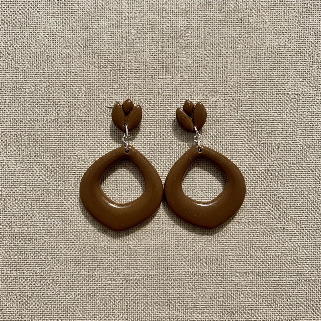 Flat lay of Crafty Larder Tulip Loop Earrings in Bronze Brown on a natural linen surface — handmade polymer clay dangle earrings in warm earthy olive-brown