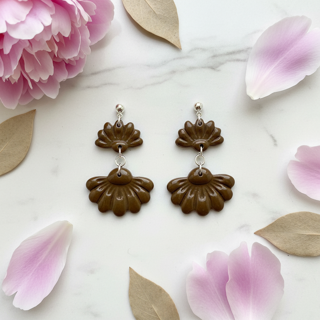 Flat lay of Crafty Larder Petal Tier Earrings in Bronze Brown on white marble with scattered petals — handmade polymer clay two-tiered ruffled drop earrings in deep olive-brown