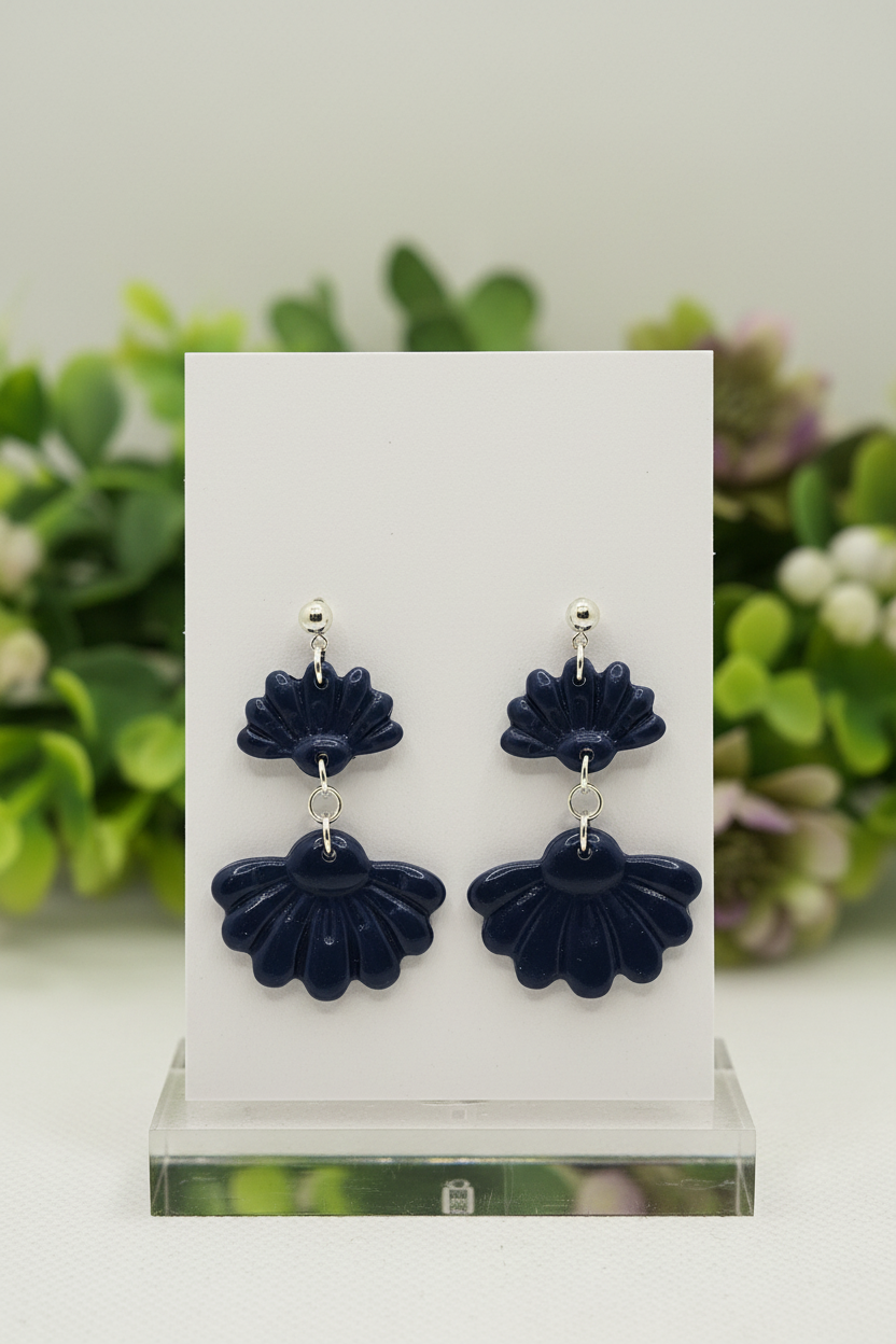 Handmade polymer clay Petal Tier Earrings in Crown Blue — deep midnight navy two-tiered ruffled flower drops with silver ball stud, displayed on a plain white jewellery card with soft botanical background