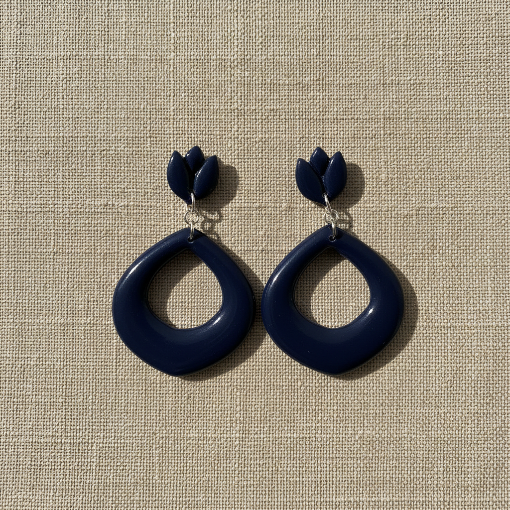 Flat lay of Crafty Larder Tulip Loop Earrings in Crown Blue on a natural linen surface — handmade polymer clay dangle earrings in deep midnight navy