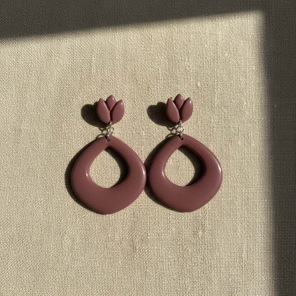 Flat lay of Crafty Larder Tulip Loop Earrings in Damson on a natural linen surface — handmade polymer clay dangle earrings in muted dusty plum