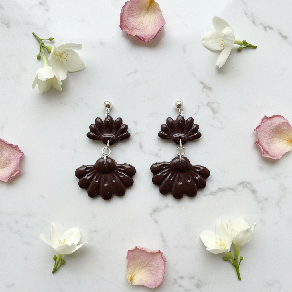 Flat lay of Crafty Larder Petal Tier Earrings in French Roast on white marble with scattered petals — handmade polymer clay two-tiered ruffled drop earrings in deep espresso brown