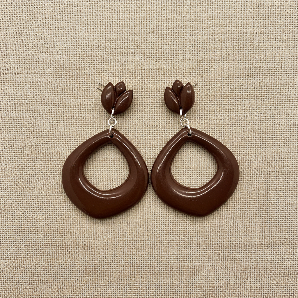 Flat lay of Crafty Larder Tulip Loop Earrings in Hot Chocolate on a natural linen surface — handmade polymer clay dangle earrings in deep dark warm brown
