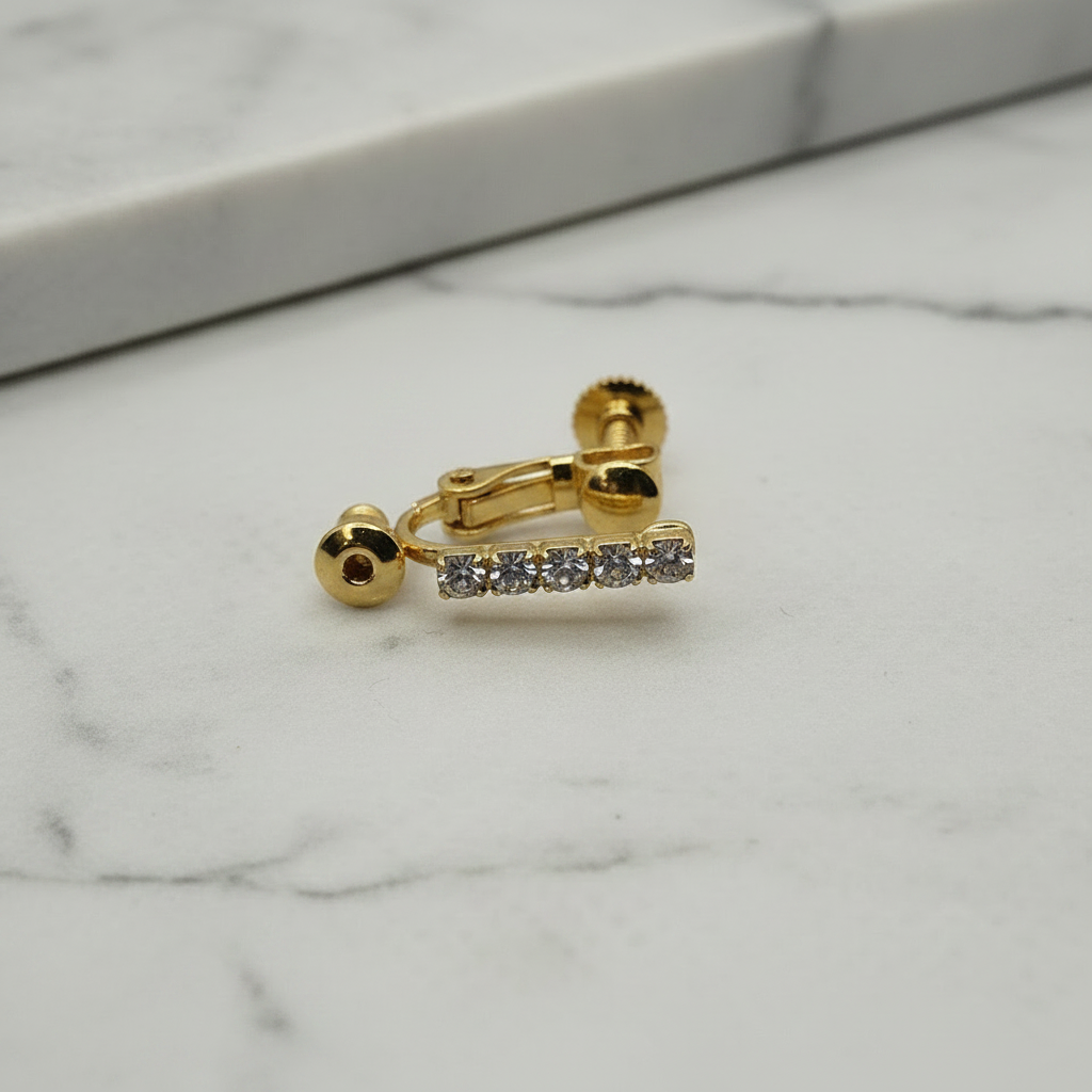 Close-up macro of 18k gold plated clip-on converter showing sparkling crystal rhinestones, on soft grey marble surface — Crafty Larder