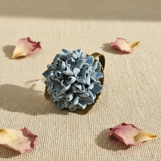Handmade polymer clay dusty blue flower ring on linen background, by Crafty Larder NZ