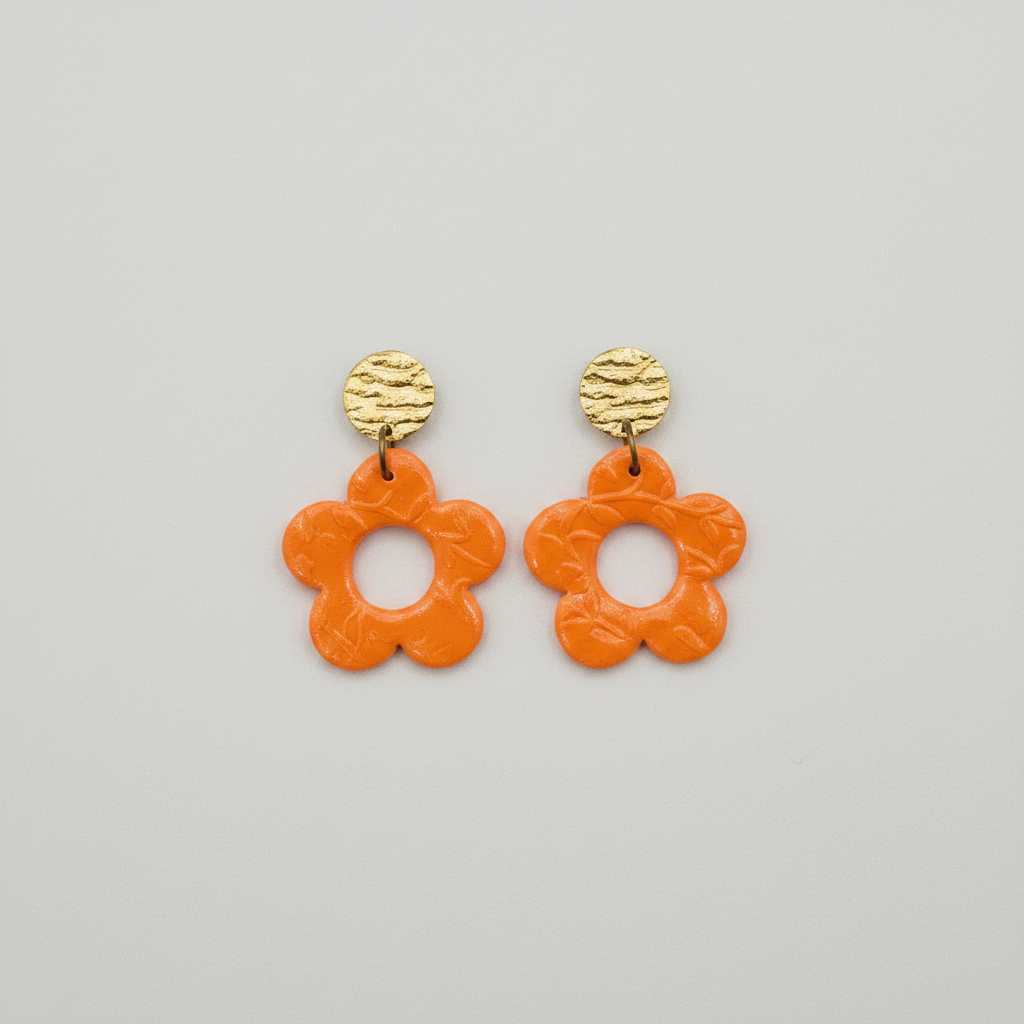 Handmade orange polymer clay open daisy drop earrings with gold textured brass stud tops, flat lay, by Crafty Larder NZ