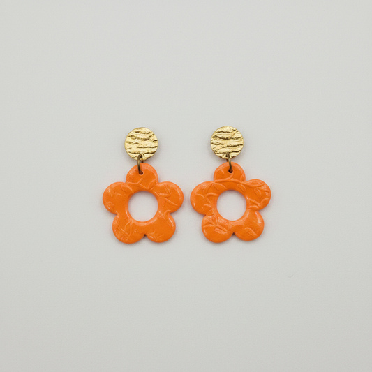 Handmade orange polymer clay open daisy drop earrings with gold textured brass stud tops, flat lay, by Crafty Larder NZ