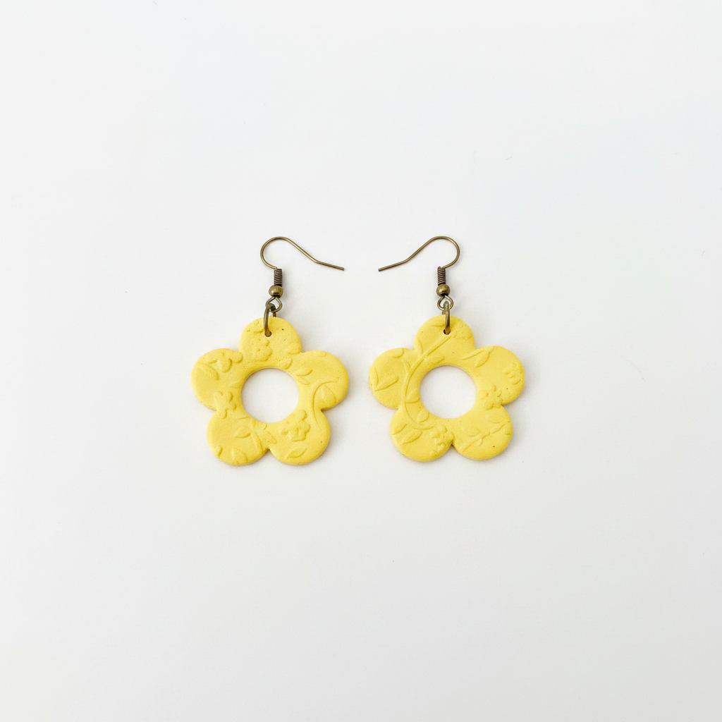 Handmade bright yellow polymer clay open daisy drop earrings with brass hooks on white surface, by Crafty Larder NZ