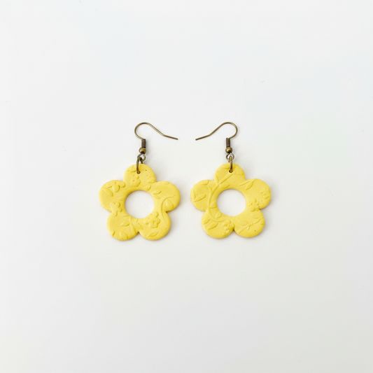 Handmade bright yellow polymer clay open daisy drop earrings with brass hooks on white surface, by Crafty Larder NZ