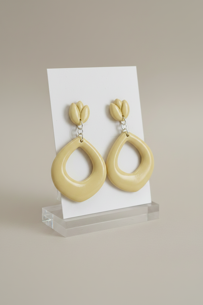 Handmade polymer clay Tulip Loop Earrings in Lemon Grass — soft pale creamy yellow tulip stud top with open teardrop hoop drop, displayed on a plain white jewellery card on a clear acrylic stand