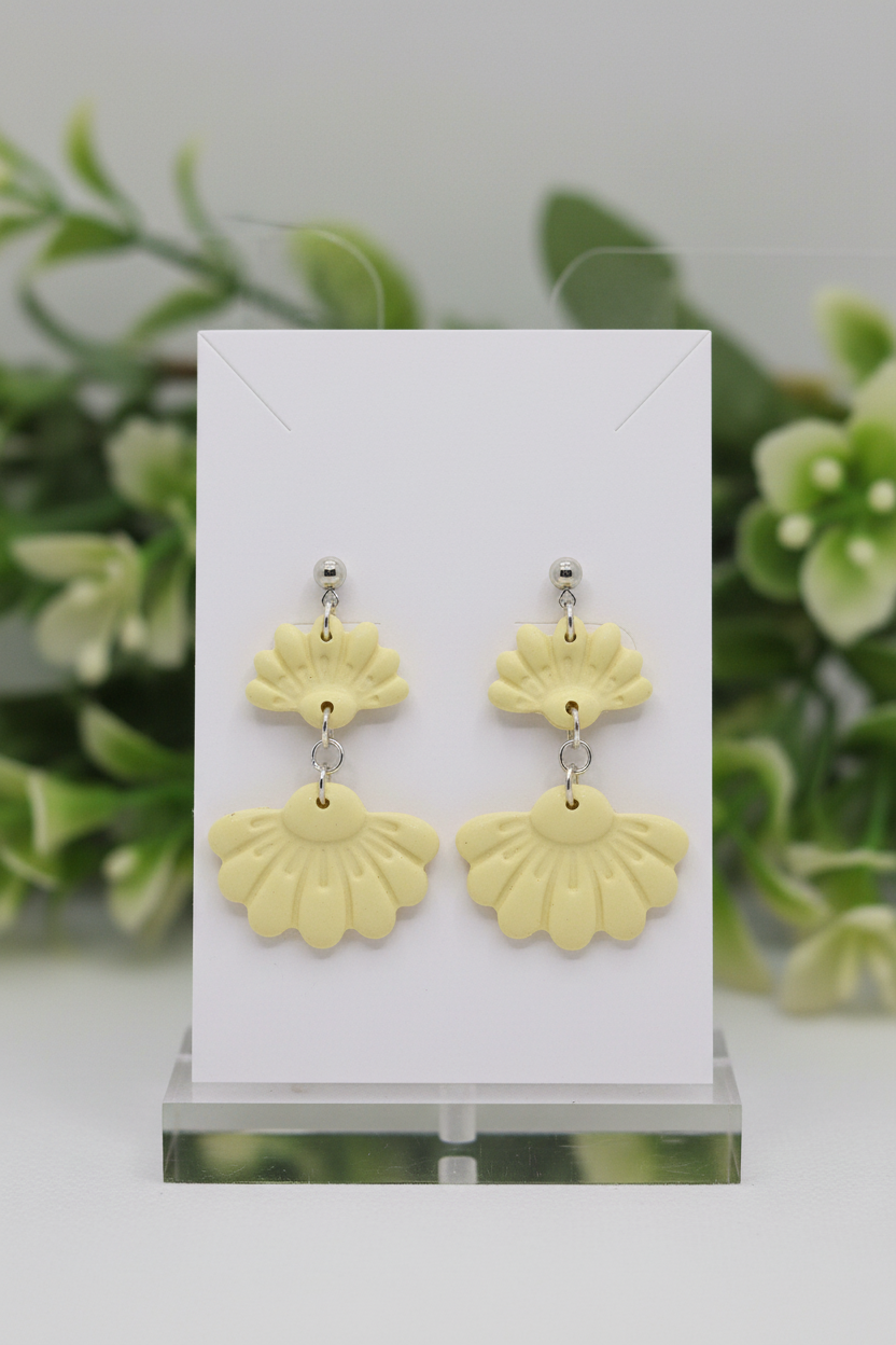 Handmade polymer clay Petal Tier Earrings in Lemon Grass — soft butter yellow two-tiered fan-shaped ruffled drops with silver ball stud, displayed on a plain white jewellery card with soft botanical background