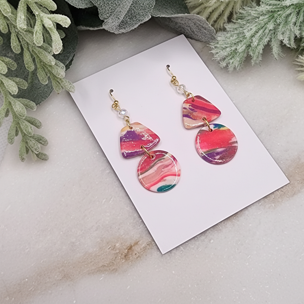"Handmade polymer clay mini geometric marble earrings with pink purple orange swirl pattern, gold connectors and crystal accents"