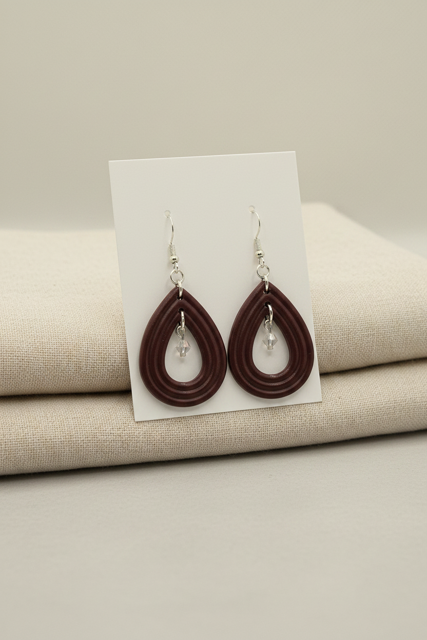 Handmade polymer clay Raindrop Crystal Earrings in Mauve Wine — deep dark burgundy open teardrop hoop earrings with crystal bead drop, displayed on a plain white jewellery card propped against linen