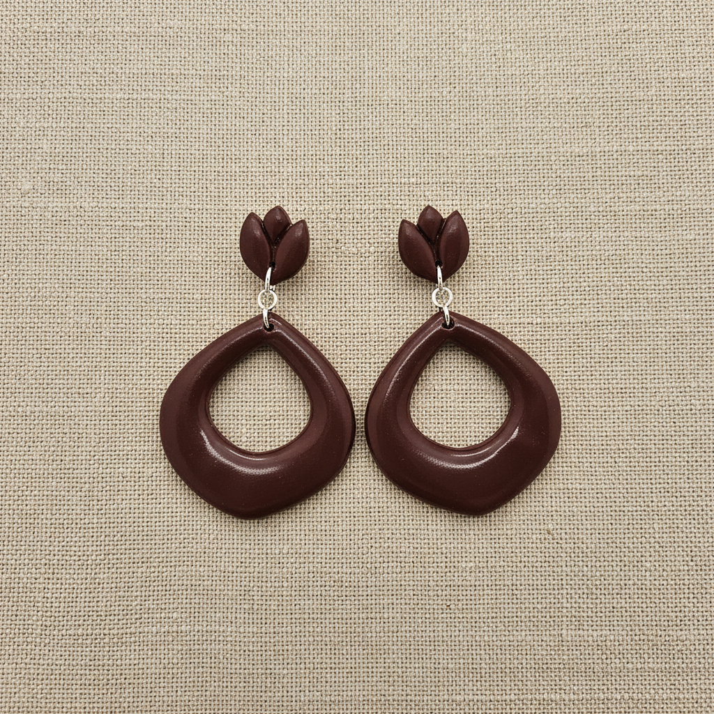 Flat lay of Crafty Larder Tulip Loop Earrings in Mauve Wine on a natural linen surface — handmade polymer clay dangle earrings in deep dark burgundy