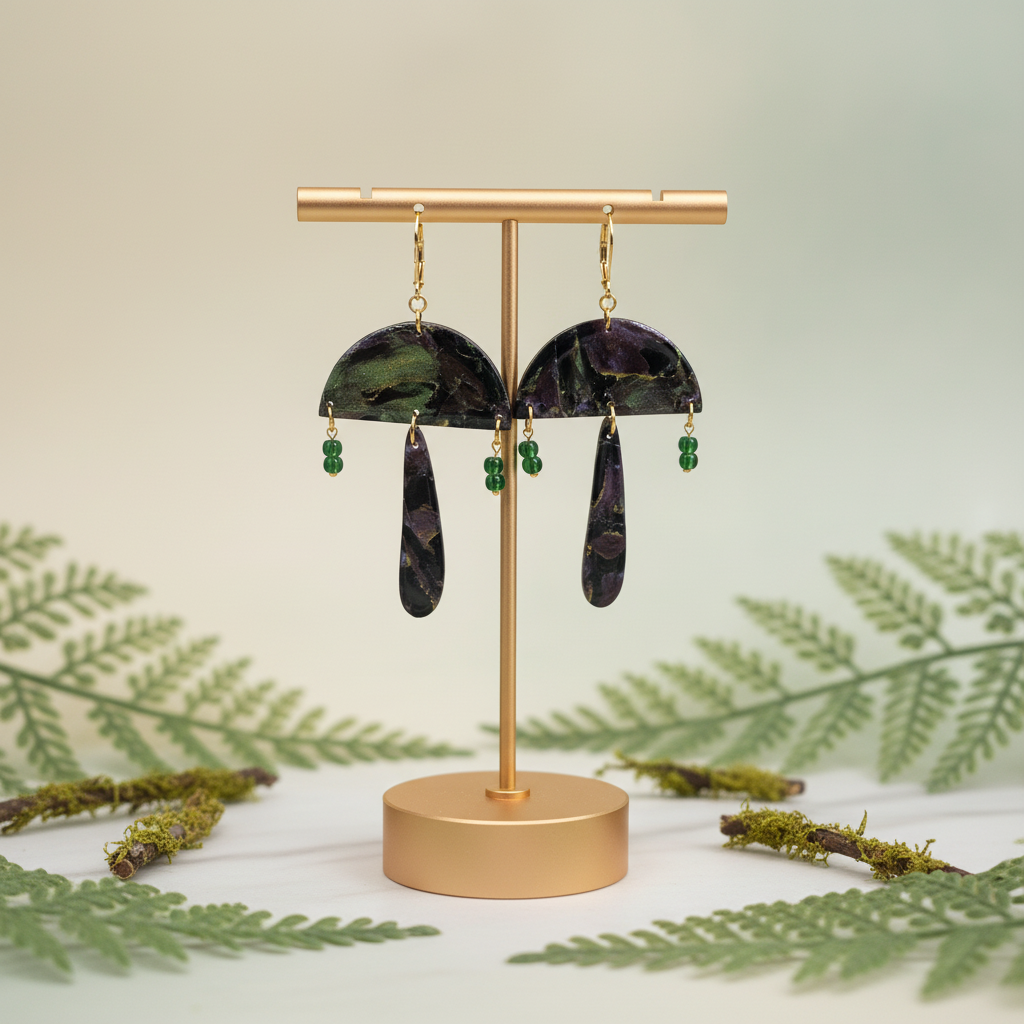  "Handmade polymer clay mushroom earrings with gold leverback hooks, green/purple/black mica shimmer mushroom caps, dark purple/black stem dangles and tiny green glass bead accents"
