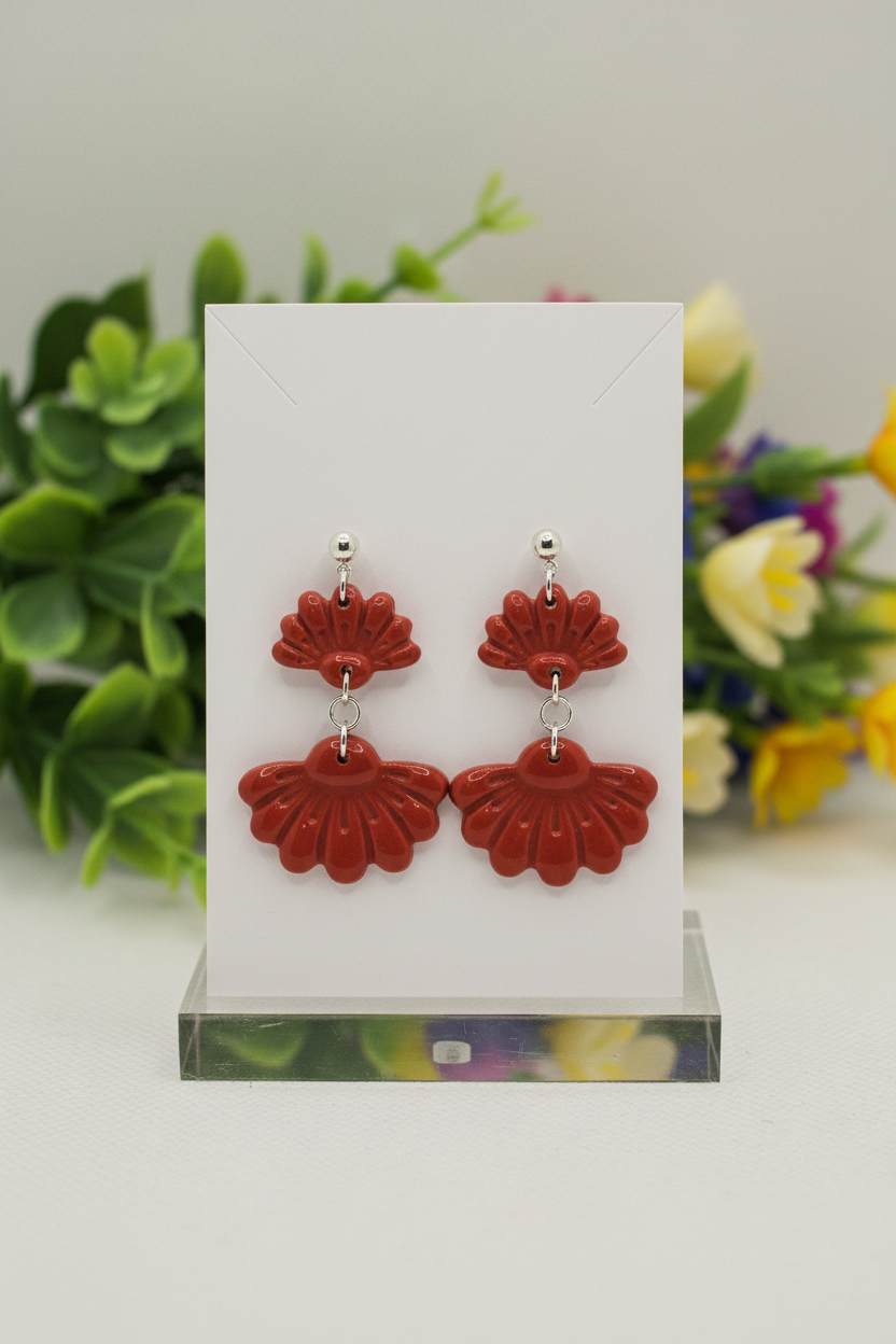 Handmade polymer clay Petal Tier Earrings in Poppy Red — warm brick red two-tiered ruffled flower drops with silver ball stud, displayed on a plain white jewellery card with soft botanical background