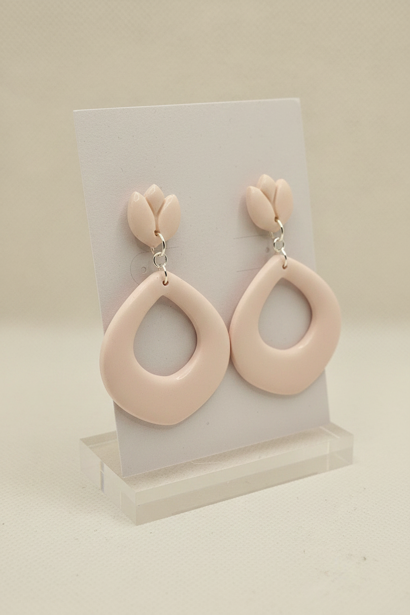 Handmade polymer clay Tulip Loop Earrings in Primrose Pink — soft pale blush pink tulip stud top with open teardrop hoop drop, displayed on a plain white jewellery card on a clear acrylic stand