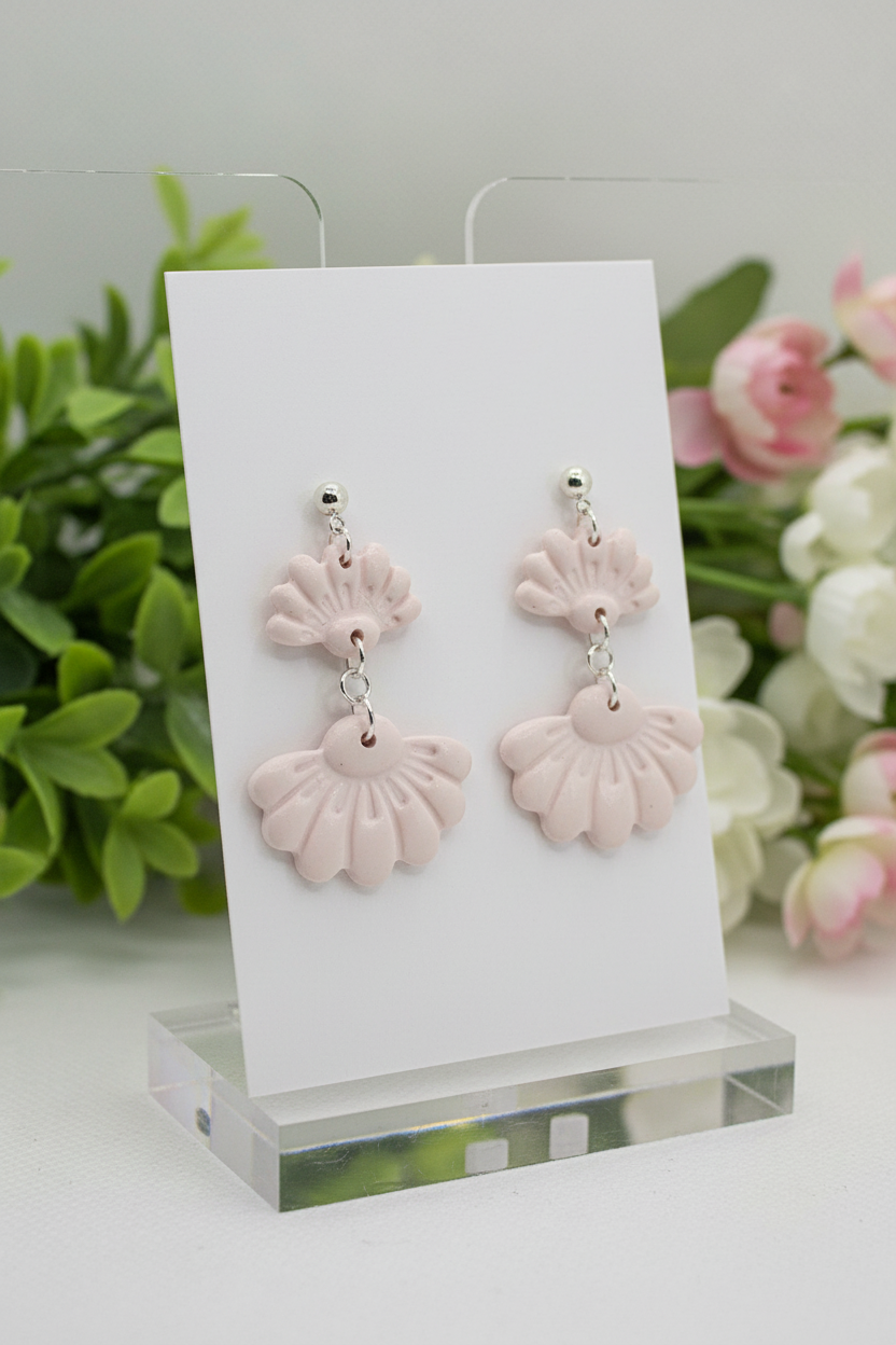 Handmade polymer clay Petal Tier Earrings in Primrose Pink — soft pale blush two-tiered fan-shaped ruffled drops with silver ball stud, displayed on a plain white jewellery card with soft botanical background