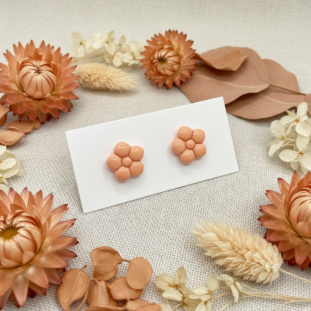 Primrose Studs in Brandied Melon — handmade polymer clay flower stud earrings with smooth glossy bubble petal finish, displayed on white card with dried peach strawflowers and soft apricot botanical styling, handcrafted in New Zealand by Crafty Larder