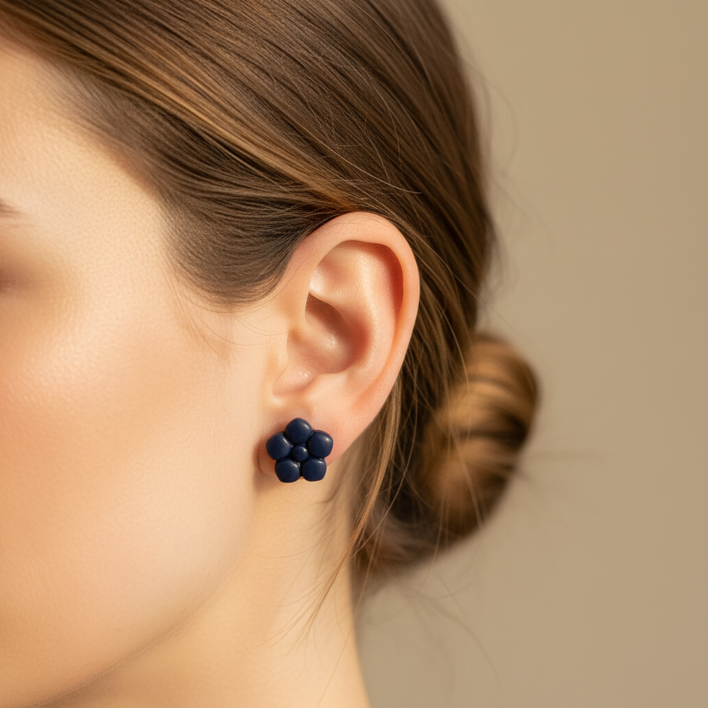 Woman wearing a Primrose Stud in Crown Blue, deep dark navy blue polymer clay flower stud with smooth rounded bubble petals, handcrafted in New Zealand by Crafty Larder
