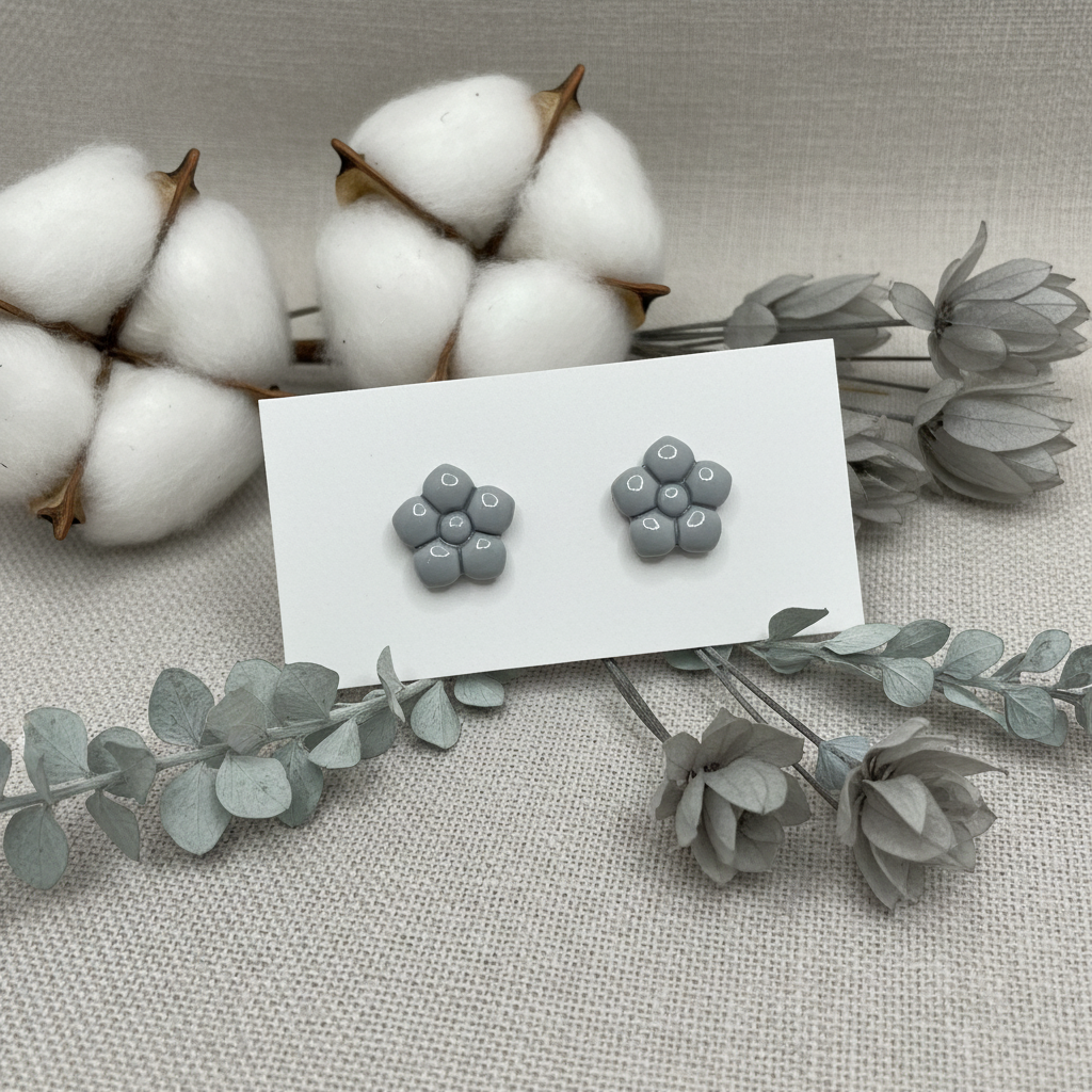 Primrose Studs in Vapor Blue — handmade polymer clay flower stud earrings with smooth glossy bubble petal finish, displayed on white card with soft grey dried cotton stems and silver-blue botanical styling, handcrafted in New Zealand by Crafty Larder