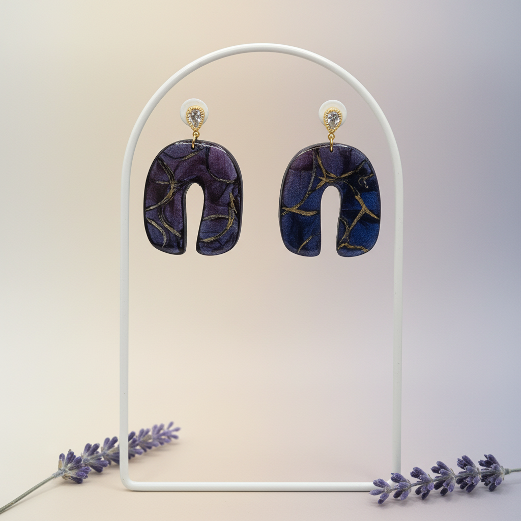 "Handmade polymer clay U-shaped arch earrings with gold textured teardrop stud posts and purple/blue mica shimmer dangles with gold marbling"