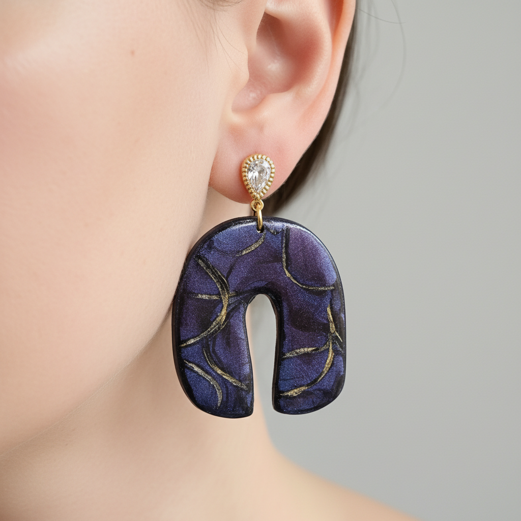"Handmade polymer clay U-shaped arch earrings with gold textured teardrop stud posts and purple/blue mica shimmer dangles with gold marbling"