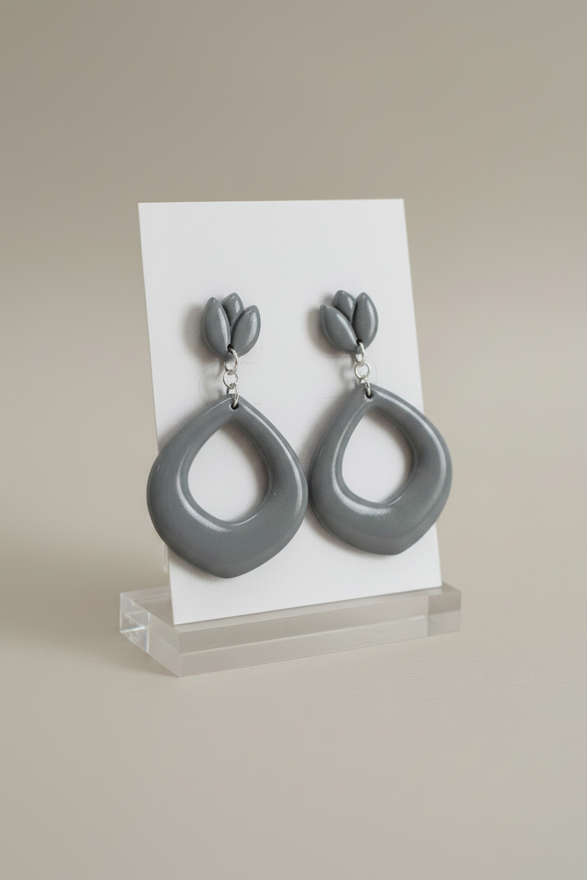 Handmade polymer clay Tulip Loop Earrings in Vapor Blue — cool muted grey-blue tulip stud top with open teardrop hoop drop, displayed on a plain white jewellery card on a clear acrylic stand