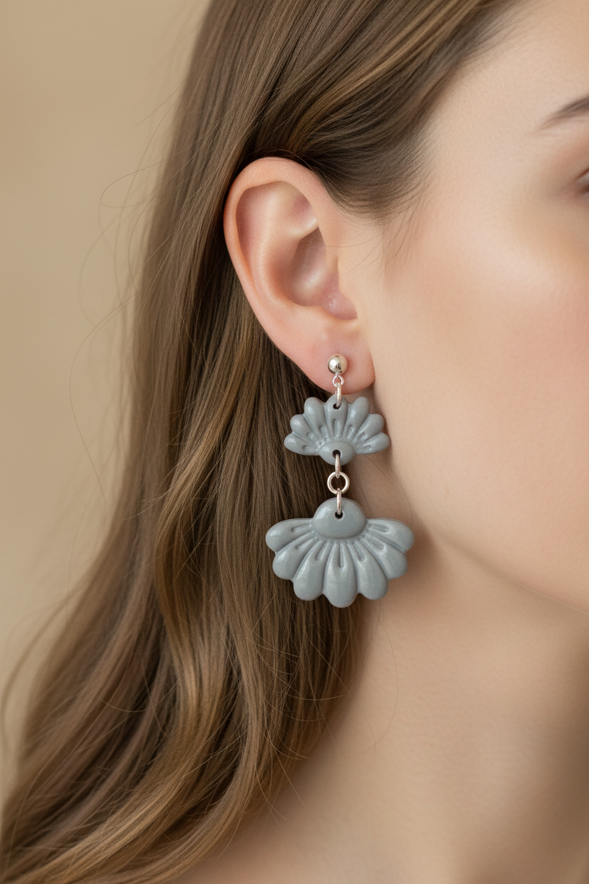 Close up of model wearing Crafty Larder Petal Tier Earrings in Vapor Blue — handmade polymer clay two-tiered fan-shaped ruffled drop earrings in soft cool grey-blue