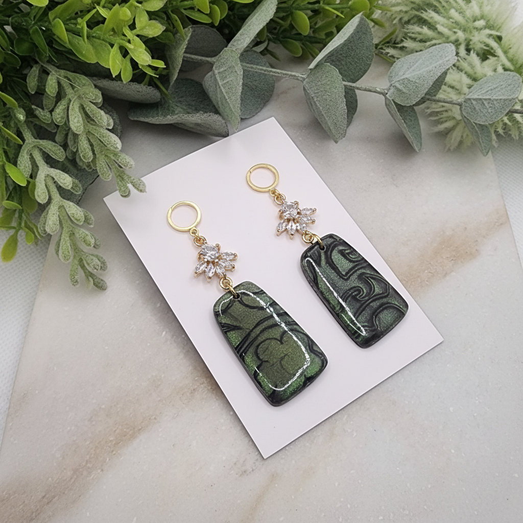 "Handmade polymer clay fob drop earrings with gold hollow circle stud posts, sparkling cubic zirconia snowflake connectors and dark green/emerald mica shimmer rectangular dangles"