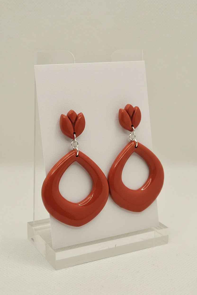 Handmade polymer clay Tulip Loop Earrings in Winterberry — warm terracotta red tulip stud top with open teardrop hoop drop, displayed on a plain white jewellery card on a clear acrylic stand