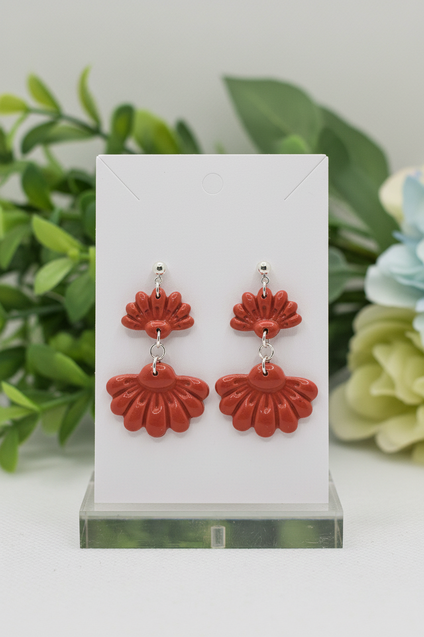 Handmade polymer clay Petal Tier Earrings in Winterberry — warm terracotta red two-tiered ruffled flower drops with silver ball stud, displayed on a plain white jewellery card with soft botanical background